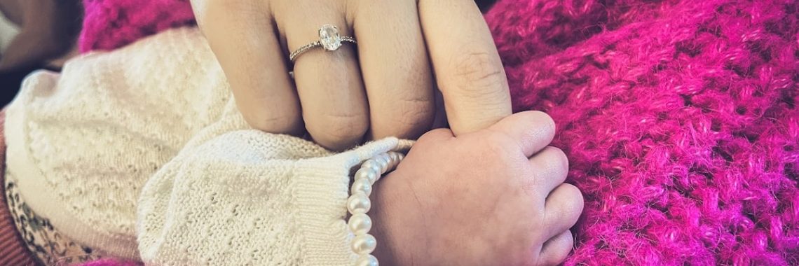 Mother holding newborn baby's hand with ring